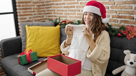 Photo for Young pregnant woman unpacking pyjama of christmas gift at home - Royalty Free Image