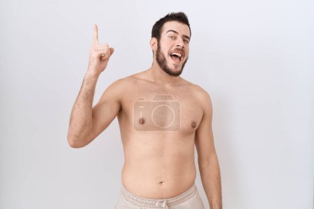 Photo for Young hispanic man standing shirtless over white background pointing finger up with successful idea. exited and happy. number one. - Royalty Free Image