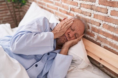 Téléchargez les photos : Moyen âge homme aux cheveux gris stressé couché sur le lit dans la chambre - en image libre de droit