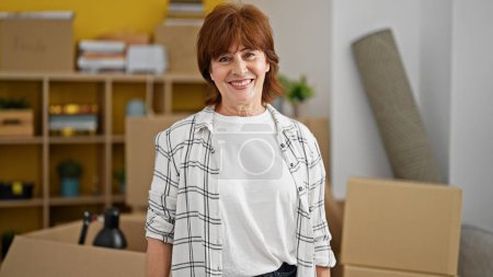 Foto de Mujer de mediana edad sonriendo confiada de pie en un nuevo hogar - Imagen libre de derechos