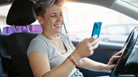Téléchargez les photos : Young woman using smartphone sitting on car at street - en image libre de droit