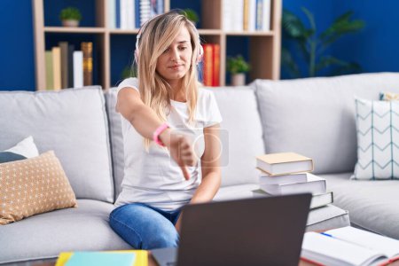 Photo for Young blonde woman studying using computer laptop at home looking unhappy and angry showing rejection and negative with thumbs down gesture. bad expression. - Royalty Free Image