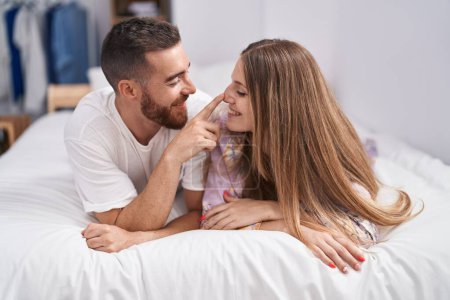 Téléchargez les photos : Homme et femme couple souriant confiant couché sur le lit dans la chambre - en image libre de droit