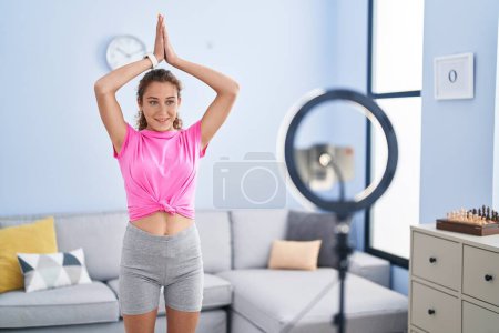 Foto de Joven hermosa mujer hispana sonriendo confiada teniendo clase de yoga en línea en casa - Imagen libre de derechos