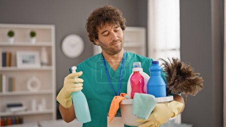 Téléchargez les photos : Jeune homme hispanique nettoyeur professionnel tenant des produits propres à la maison - en image libre de droit