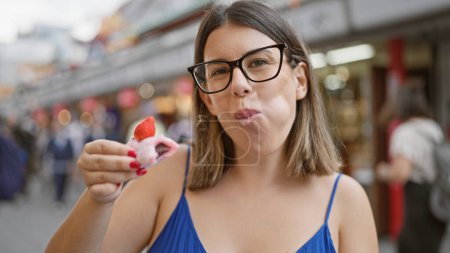 Téléchargez les photos : Belle femme hispanique savoure mochi fraise sur la rue nakamise - en image libre de droit