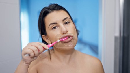 Téléchargez les photos : Jeune belle femme hispanique brossant des dents dans la salle de bain - en image libre de droit