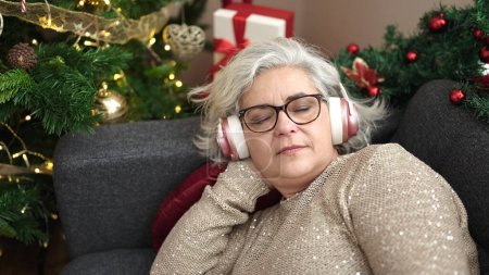 Photo for Middle age woman with grey hair sleeping on sofa by christmas tree at home - Royalty Free Image
