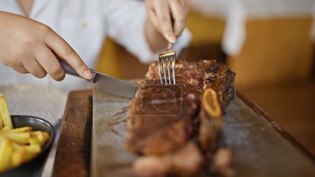 Téléchargez les photos : Jeune femme sculptant de la viande au restaurant - en image libre de droit