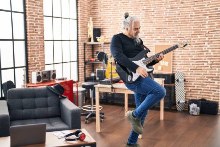 Téléchargez les photos : Moyen Age homme aux cheveux gris musicien jouant de la guitare électrique dansant au studio de musique - en image libre de droit