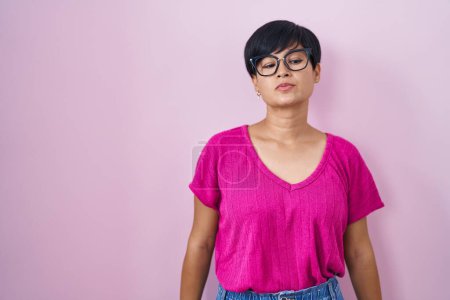 Photo for Young asian woman with short hair standing over pink background relaxed with serious expression on face. simple and natural looking at the camera. - Royalty Free Image