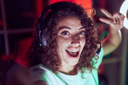 Téléchargez les photos : Young beautiful hispanic woman streamer smiling confident make selfie by camera at gaming room - en image libre de droit