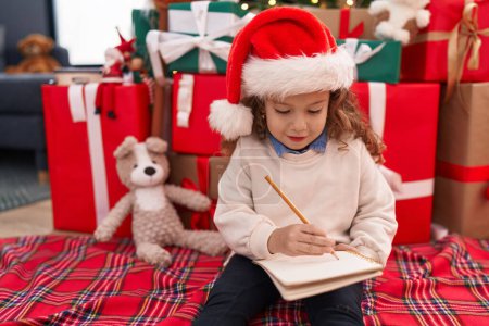 Photo for Adorable blonde toddler writing santa claus letter sitting on floor by christmas gifts at home - Royalty Free Image