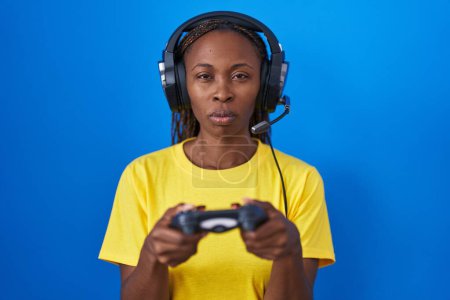 Photo for African american woman playing video games skeptic and nervous, frowning upset because of problem. negative person. - Royalty Free Image