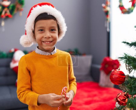 Foto de Adorable niño hispano sonriendo confiado decorando el árbol de Navidad en casa - Imagen libre de derechos