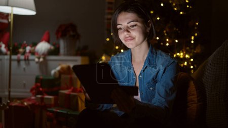 Foto de Mujer caucásica joven haciendo compras en línea de Navidad con la tableta en casa - Imagen libre de derechos
