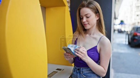 Photo for Young blonde woman holding hungary forint banknotes of cash machine at street - Royalty Free Image