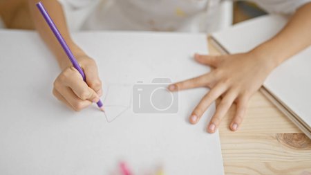 Téléchargez les photos : Adorable garçon artiste mains habilement esquisser dans la classe d'art, la peinture passe-temps évident comme il dessine dans le carnet à son bureau dans l'atelier intérieur, apprendre et embrasser sa passion. - en image libre de droit