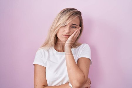 Téléchargez les photos : Jeune femme blonde debout sur fond rose pensant fatigué et ennuyé avec des problèmes de dépression avec les bras croisés. - en image libre de droit
