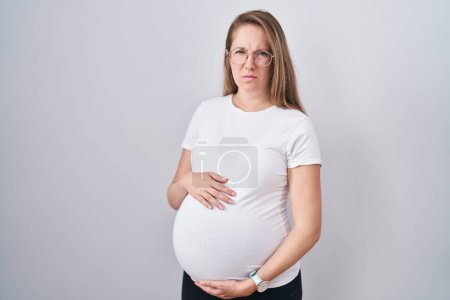 Foto de Mujer embarazada joven esperando un bebé, tocando el vientre embarazada escéptico y nervioso, frunciendo el ceño molesto debido a un problema. persona negativa. - Imagen libre de derechos