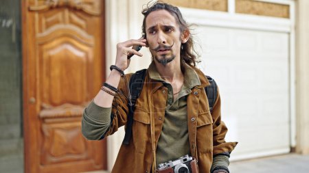 Téléchargez les photos : Jeune homme hispanique touriste parler sur smartphone regardant bouleversé à la rue - en image libre de droit