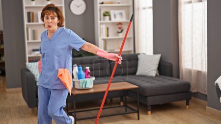Foto de Mujer de mediana edad limpiador profesional de limpieza y baile en casa - Imagen libre de derechos