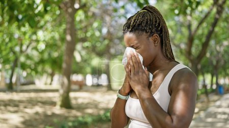 Foto de Mujer afroamericana usando tejido con alergia al polen en el parque - Imagen libre de derechos