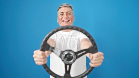 Photo for Young caucasian man smiling confident using steering wheel as a driver over isolated blue background - Royalty Free Image