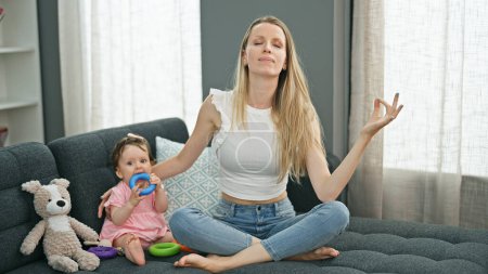 Photo for Mother and daughter doing yoga exercise while playing with hoops at home - Royalty Free Image