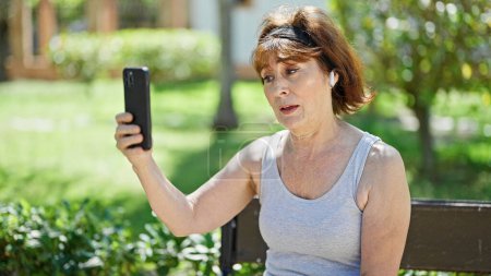 Téléchargez les photos : Femme d'âge moyen souriant confiant ayant appel vidéo au parc - en image libre de droit