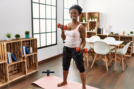 Photo for African american woman smiling confident using dumbbells training at home - Royalty Free Image