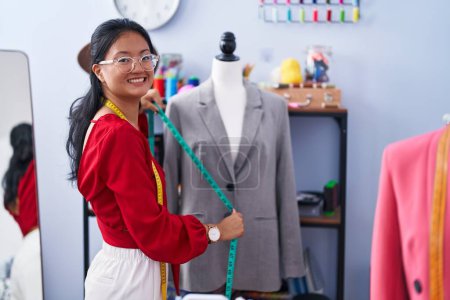 Téléchargez les photos : Jeune femme chinoise tailleur souriant confiance veste de mesure à l'atelier - en image libre de droit