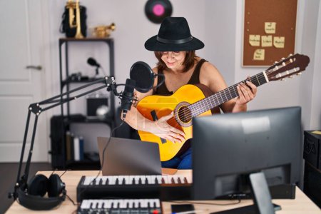Foto de Mujer de mediana edad músico que tiene concierto de guitarra clásica en línea en el estudio de música - Imagen libre de derechos