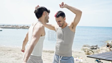 Foto de Dos hombres pareja sonriendo confiado bailando en la playa - Imagen libre de derechos
