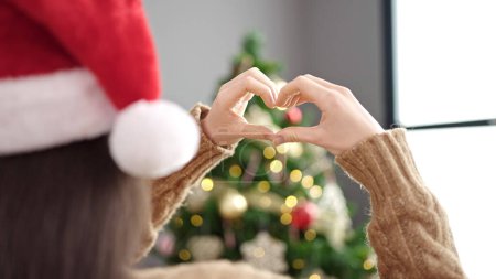 Photo for Young beautiful hispanic woman celebrating christmas doing heart shape with hands at street - Royalty Free Image