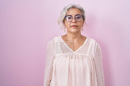 Photo for Middle age woman with grey hair standing over pink background relaxed with serious expression on face. simple and natural looking at the camera. - Royalty Free Image