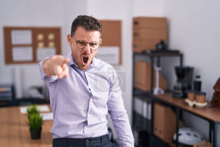Photo for Young hispanic man at the office pointing displeased and frustrated to the camera, angry and furious with you - Royalty Free Image