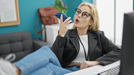 Photo for Young blonde woman business worker sending voice message by smartphone working at the office - Royalty Free Image