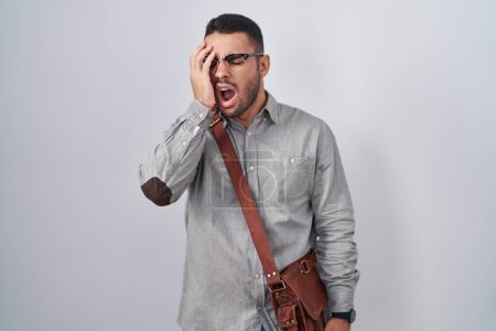 Photo for Young hispanic man wearing suitcase yawning tired covering half face, eye and mouth with hand. face hurts in pain. - Royalty Free Image