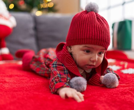 Foto de Adorable bebé caucásico tumbado en el sofá por el árbol de Navidad en casa - Imagen libre de derechos