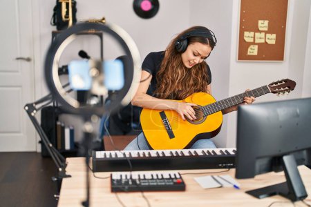 Téléchargez les photos : Jeune belle musicienne hispanique ayant cours de guitare classique en ligne au studio de musique - en image libre de droit