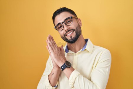 Téléchargez les photos : Jeune homme hispanique portant des vêtements de travail et des lunettes applaudissant et applaudissant heureux et joyeux, souriant mains fières ensemble - en image libre de droit
