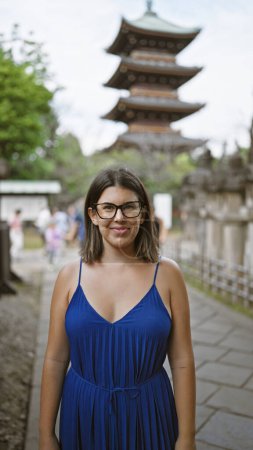 Foto de Sonriendo hermosa mujer hispana en gafas posando con confianza en ueno park templo, irradiando alegría y éxito - Imagen libre de derechos