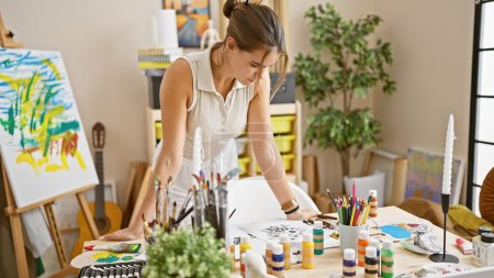 Photo for Young, beautiful hispanic woman artist confidently drawing, standing, concentrating in her buzzing art studio, immersed in creativity and learning. - Royalty Free Image
