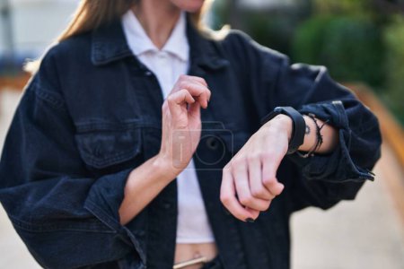 Téléchargez les photos : Jeune femme blonde touchant montre au parc - en image libre de droit