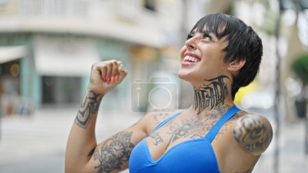 Foto de Mujer hispana con brazo amputado sonriendo confiada mirando al cielo celebrando en la calle - Imagen libre de derechos
