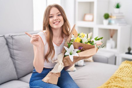 Photo for Caucasian woman holding bouquet of white flowers smiling happy pointing with hand and finger to the side - Royalty Free Image