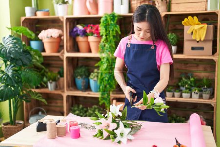 Photo for Young chinese woman florist cutting stem at flower shop - Royalty Free Image