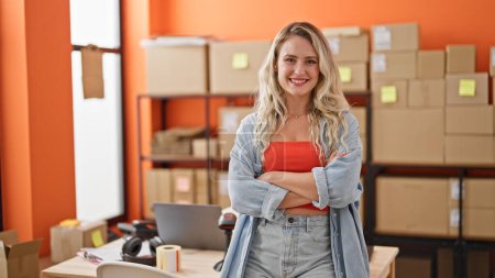 Téléchargez les photos : Jeune femme blonde ecommerce travailleur d'affaires debout avec les bras croisés geste au bureau - en image libre de droit