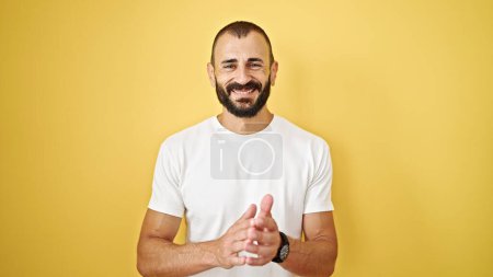 Téléchargez les photos : Jeune homme hispanique souriant confiant applaudissant sur fond jaune isolé - en image libre de droit